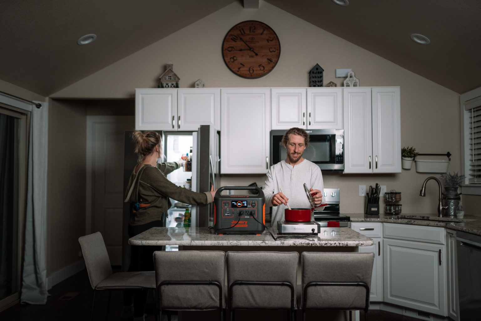 A couple uses the Jackery Explorer 1000 to power a refrigerator and countertop burner in the kitchen.